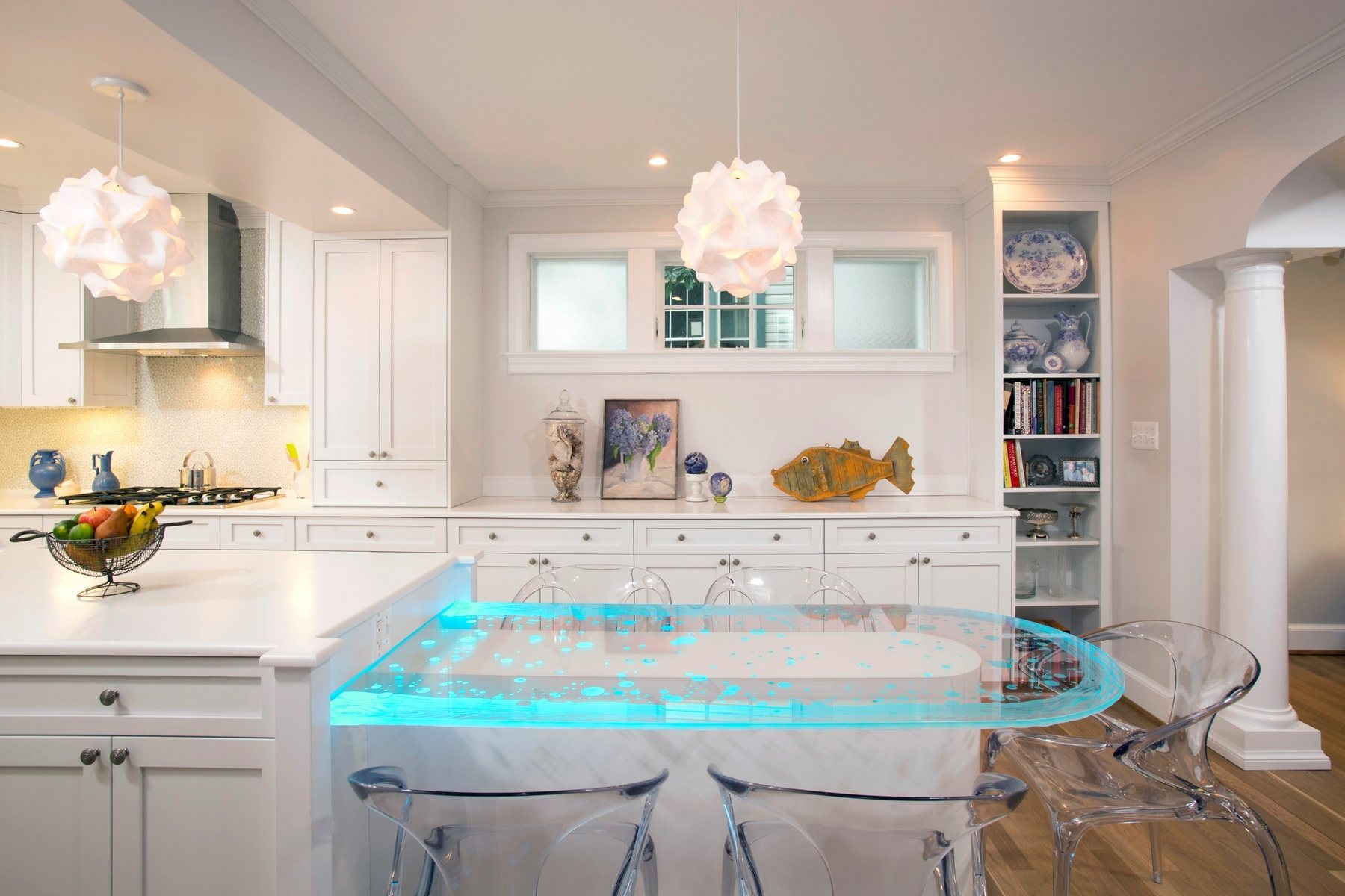 Bright white kitchen with custom cabinetry, glass features, and unique LED-lit glass breakfast table in Chevy Chase home