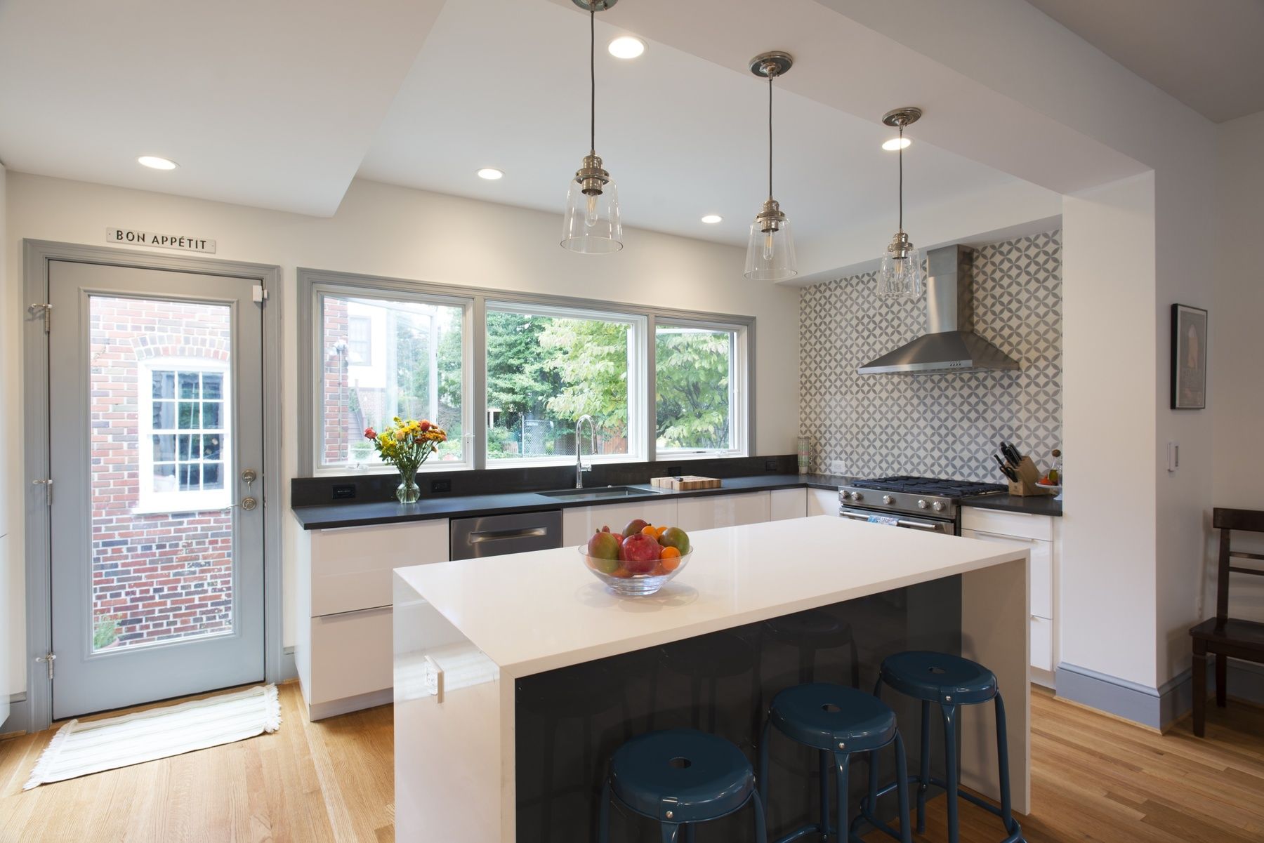 Modern, spacious kitchen featuring white cabinetry, contemporary lighting, and functional island created from formerly underutilized spaces