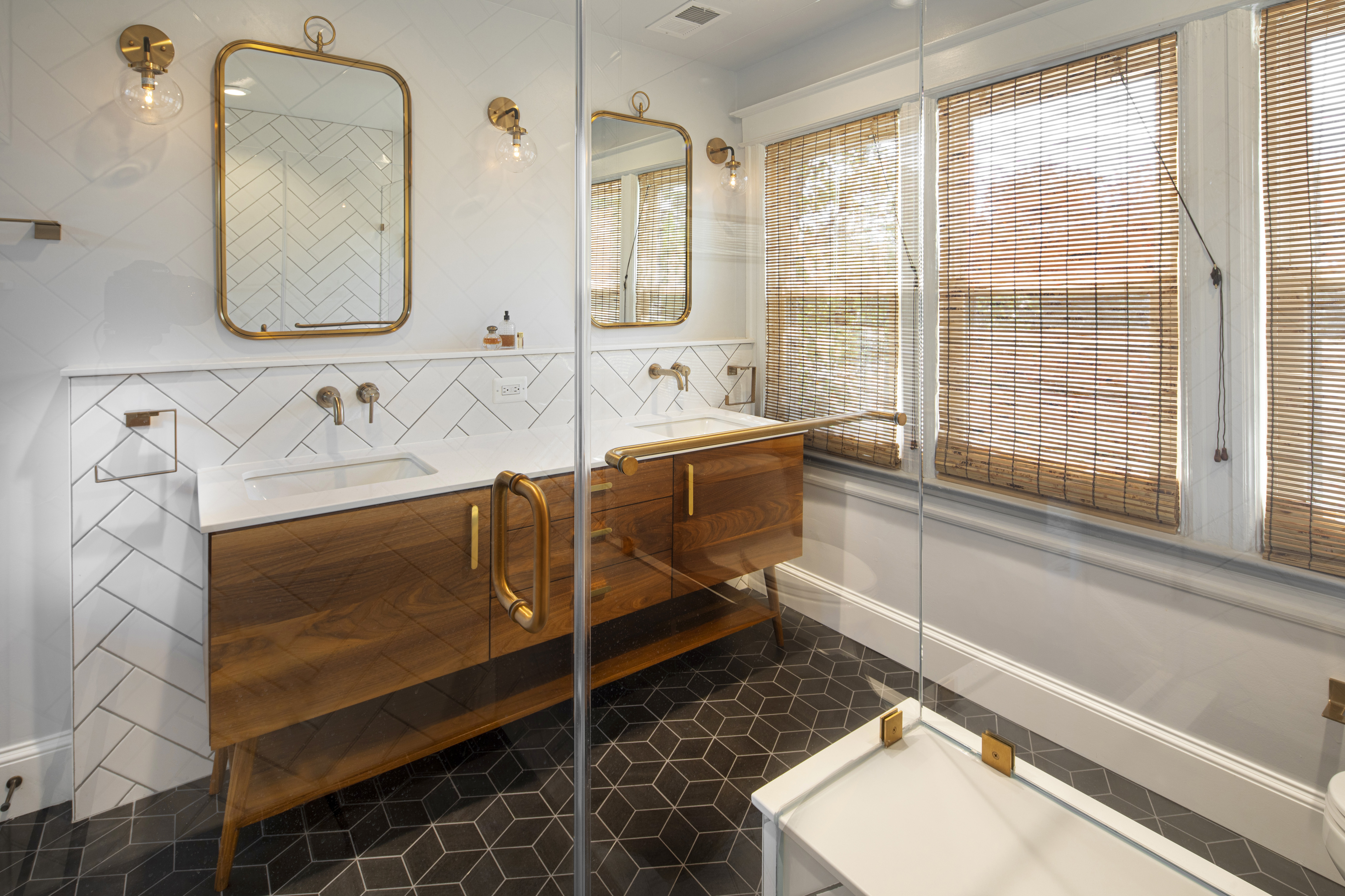 Shower area of primary bathroom featuring classic black and white tile, gold shower fixtures, and thoughtful design elements