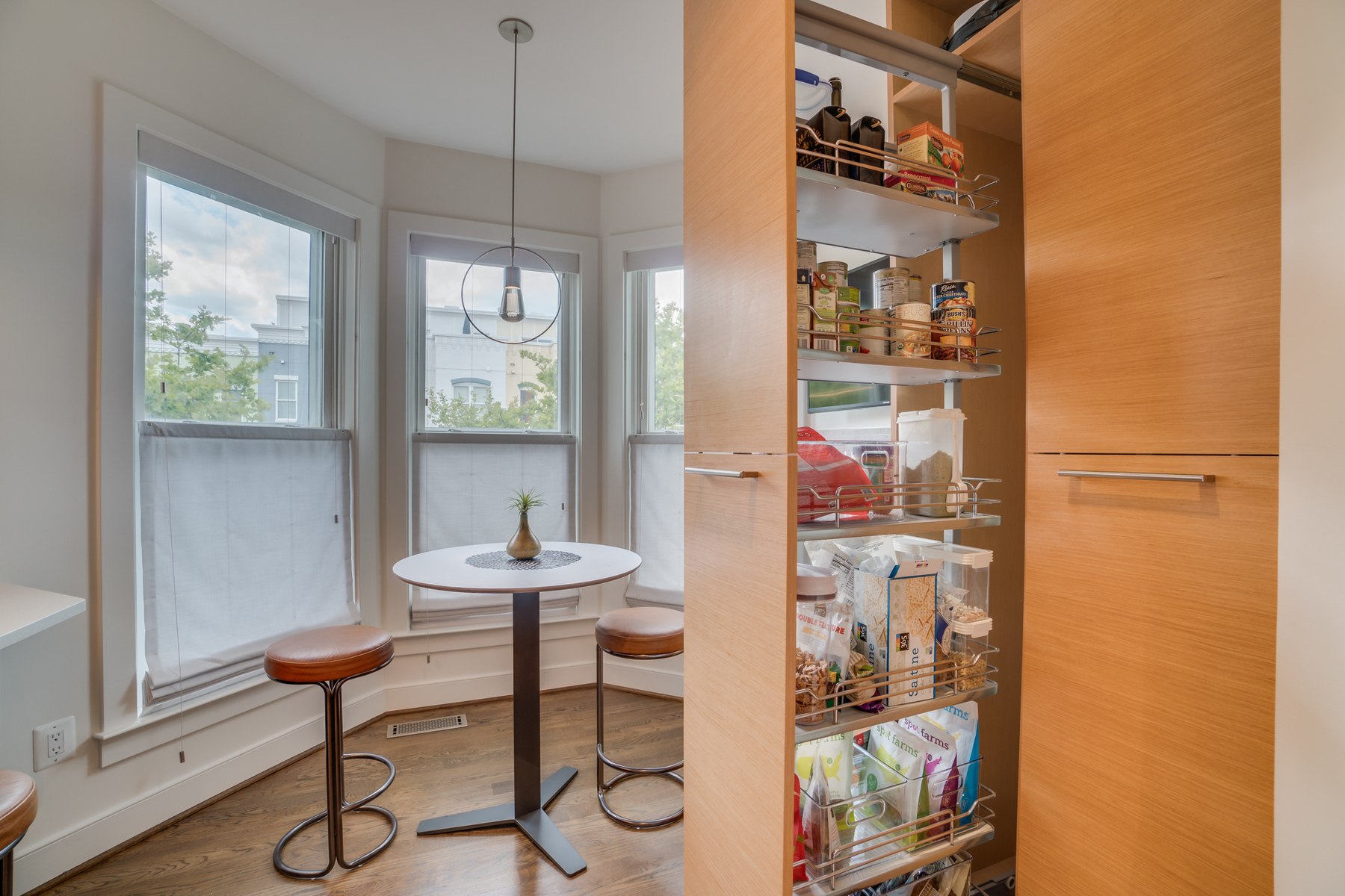 Modernized kitchen featuring light cabinetry, contemporary lighting, and customized storage solutions