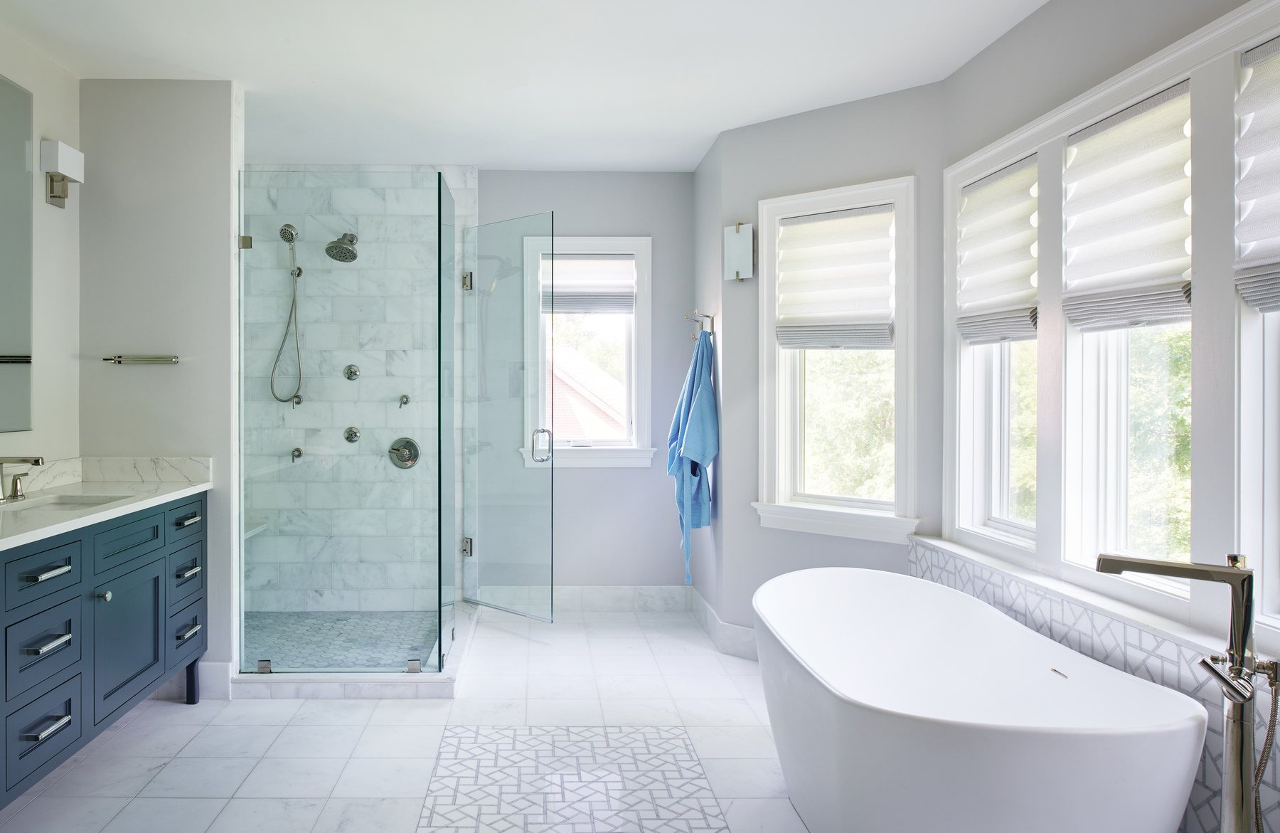 Elegant primary bathroom featuring freestanding soaking tub, custom tilework, and premium fixtures in Colonial Village home