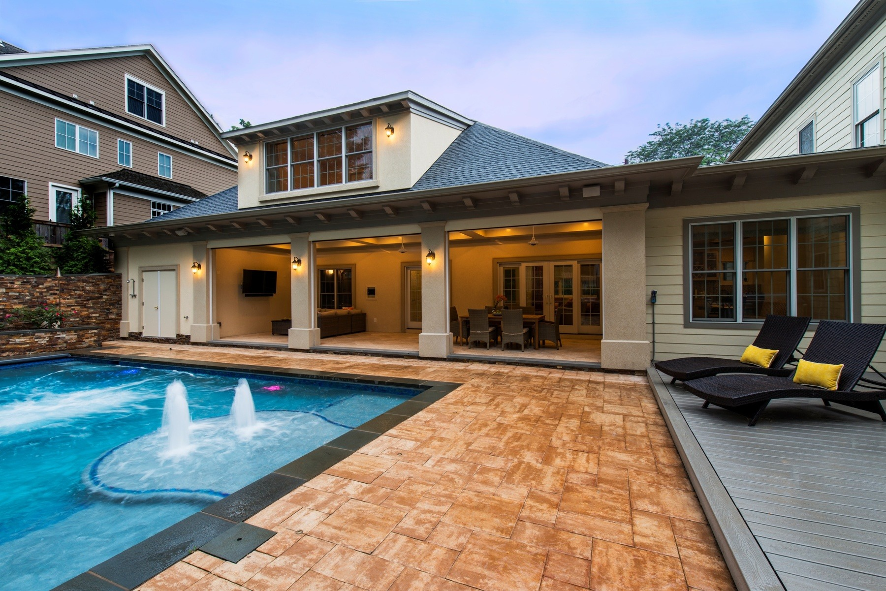 Pool, paver patio and open deck beside a covered outdoor living room with dining and lounge areas