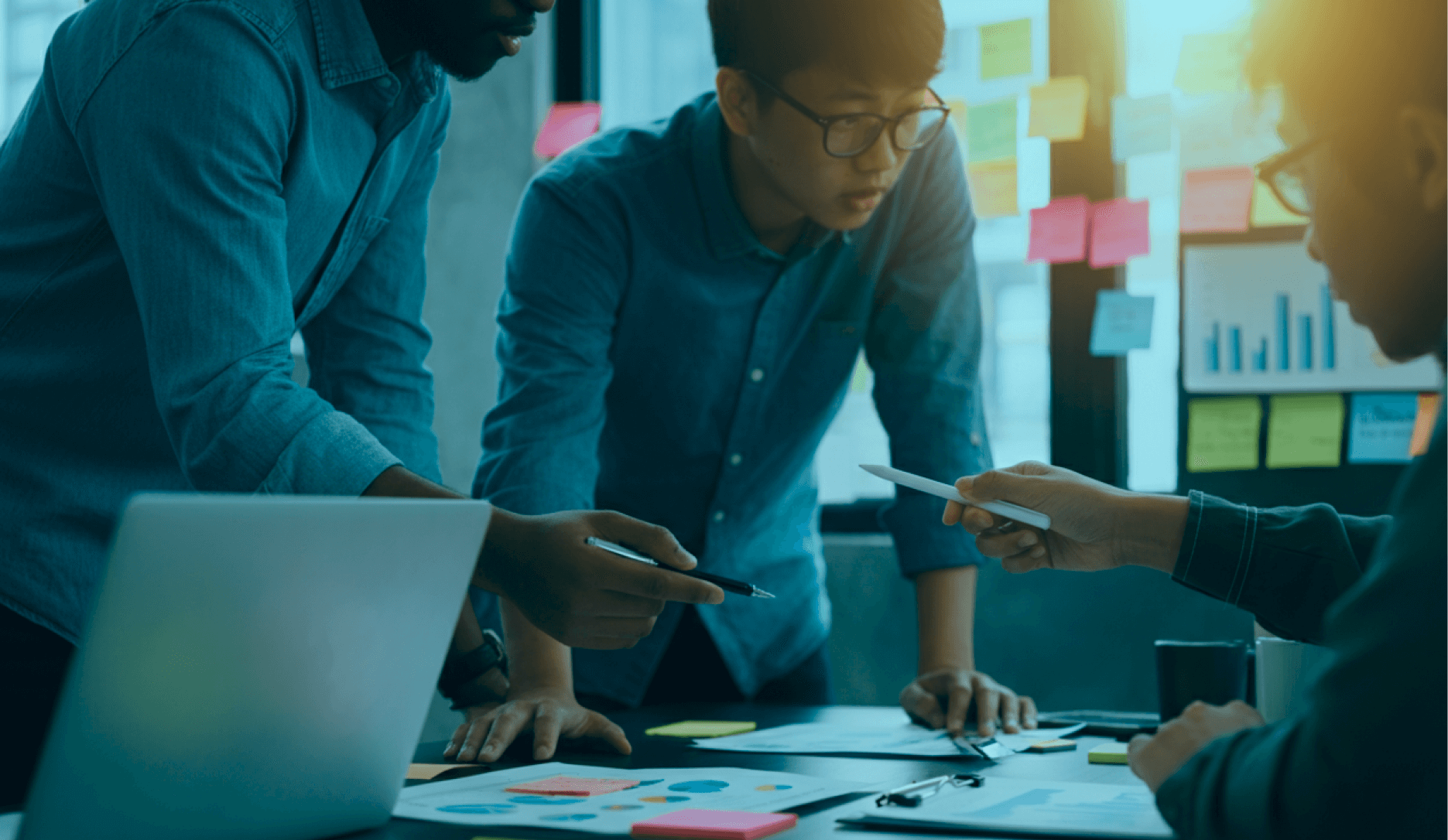 Three people are gathered around a table, likely in a meeting or brainstorming session.