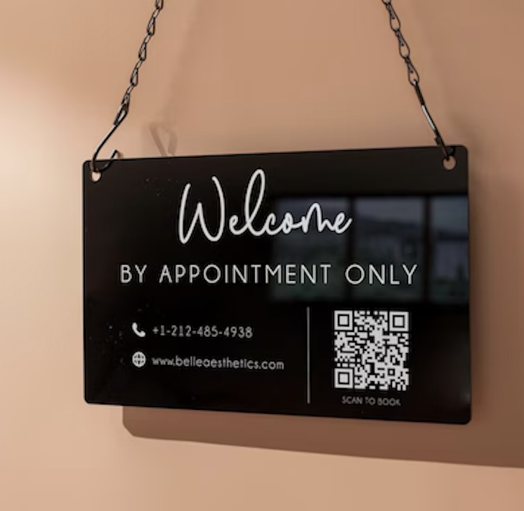 Black hanging sign on wall with QR code to schedule appointments
