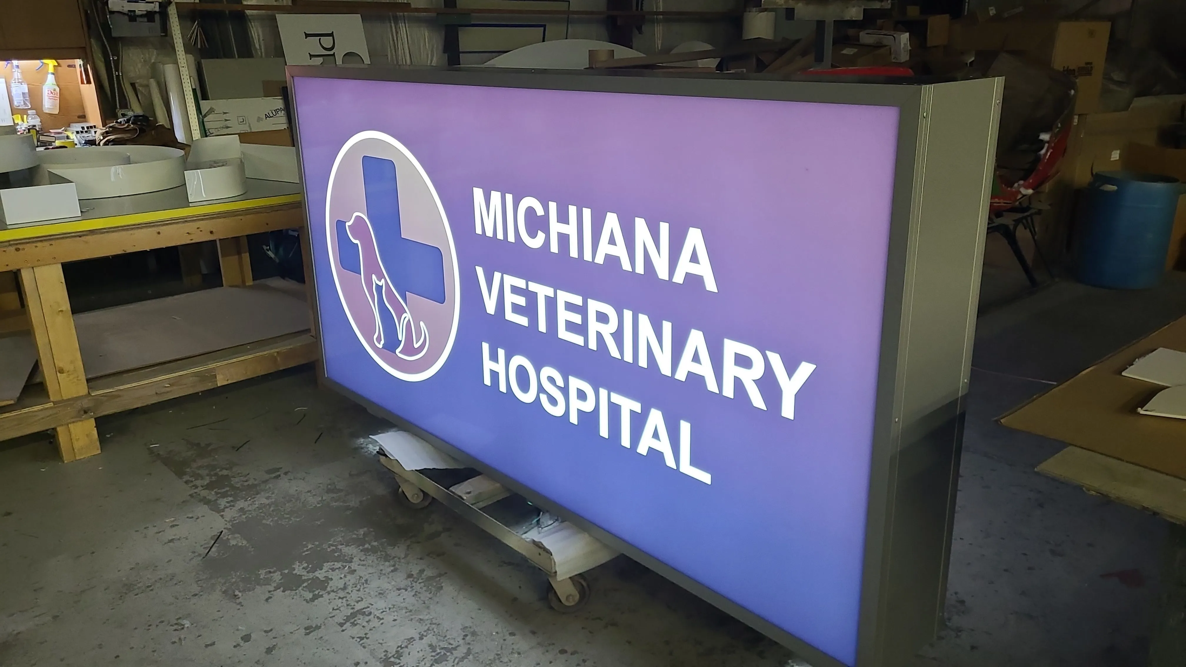Illuminated sign for Michiana Veterinary Hospital with a blue cross and animal silhouettes.