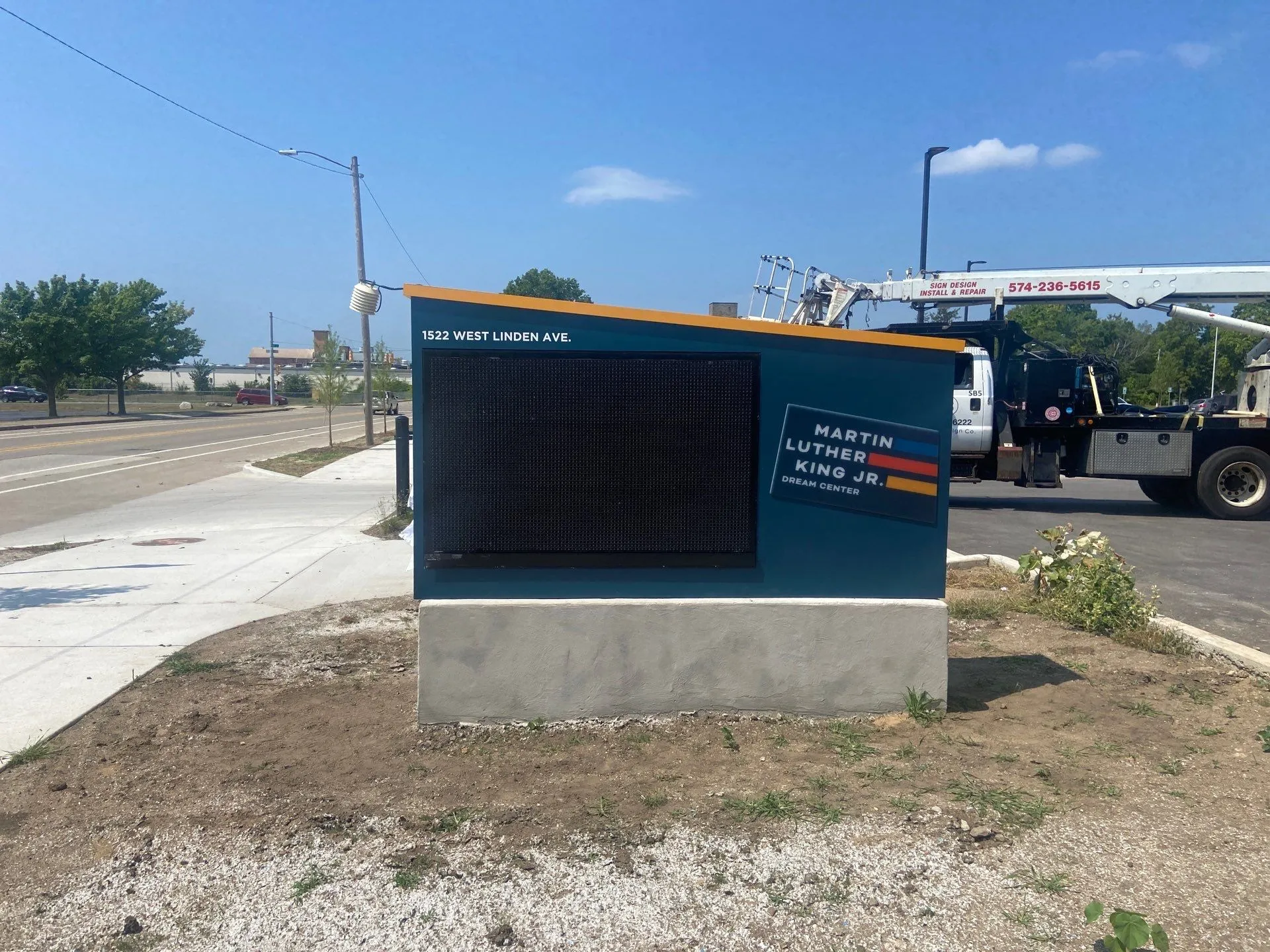Outdoor digital sign for Martin Luther King Jr. Dream Center at 1522 West Linden Ave with blue sky and a utility truck in the background.