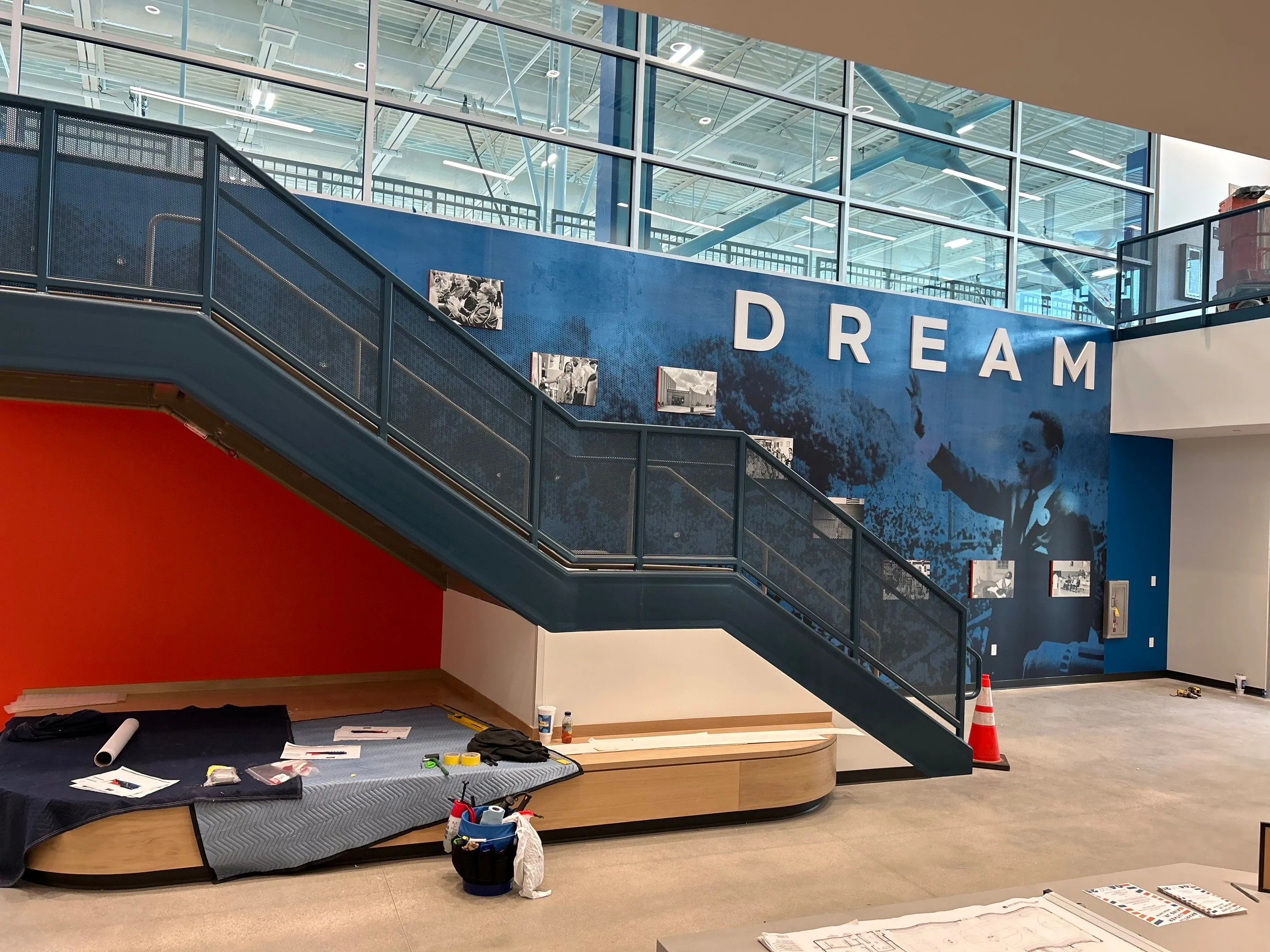 Interior of a modern building with a staircase and a large blue mural featuring Martin Luther King Jr. and the word DREAM in large letters.