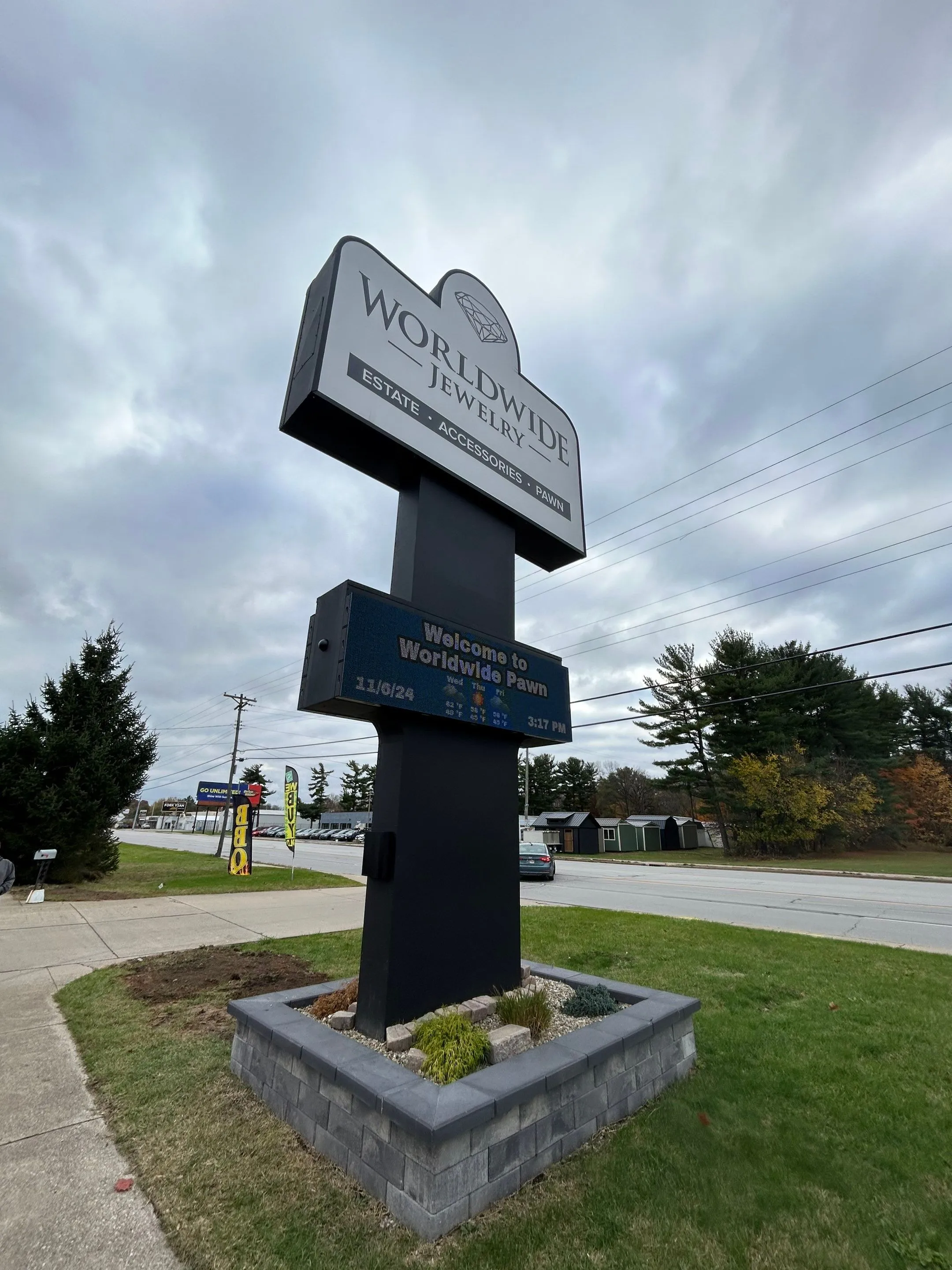 Outdoor sign for Worldwide Jewelry and Pawn on a cloudy day, with weather and time displayed below the main sign.