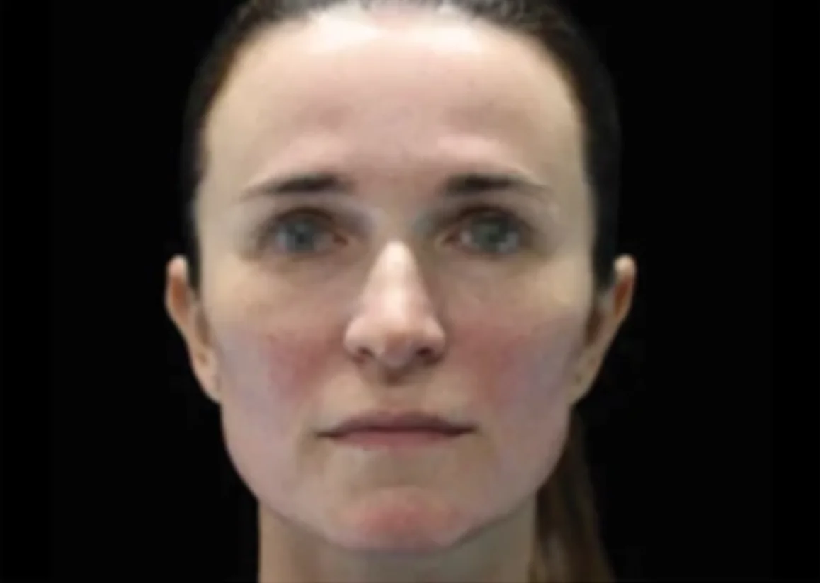 Close-up of a woman with light skin and pulled-back brown hair against a dark background.