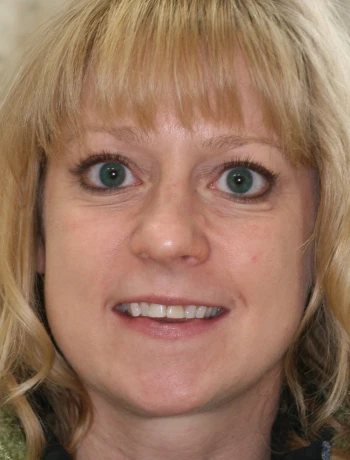 Close-up portrait of a smiling middle-aged woman with blonde hair and green eyes.