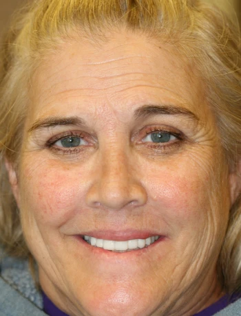 Close-up portrait of a smiling middle-aged woman with blonde hair and blue eyes.