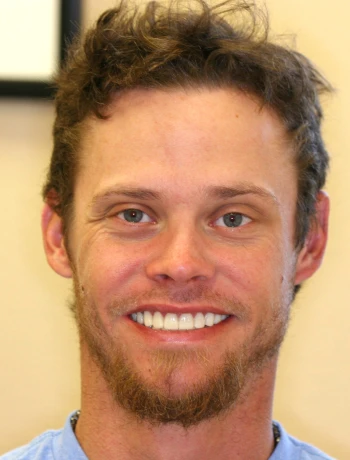 Portrait of a smiling man with short curly hair and a trimmed beard.