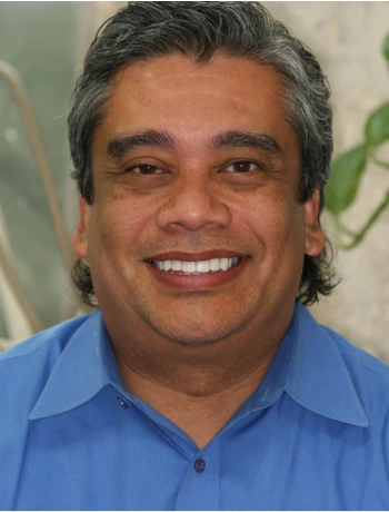 Smiling middle-aged man with salt-and-pepper hair wearing a blue collared shirt.