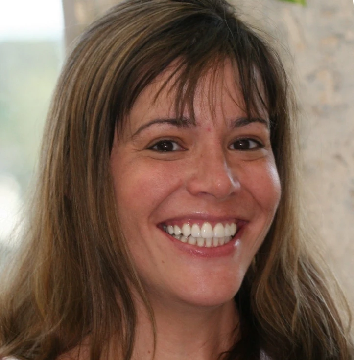 Close-up of a smiling woman with long brown hair and brown eyes.