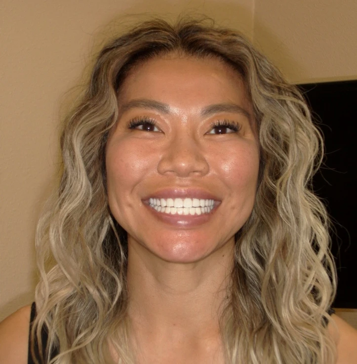 Woman with long, wavy blonde hair smiling widely, showing her teeth.