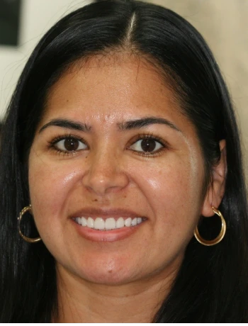Close-up portrait of a woman with long black hair, wearing gold hoop earrings and smiling.