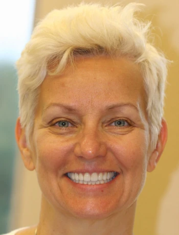 Close-up of a smiling middle-aged woman with short platinum blonde hair.