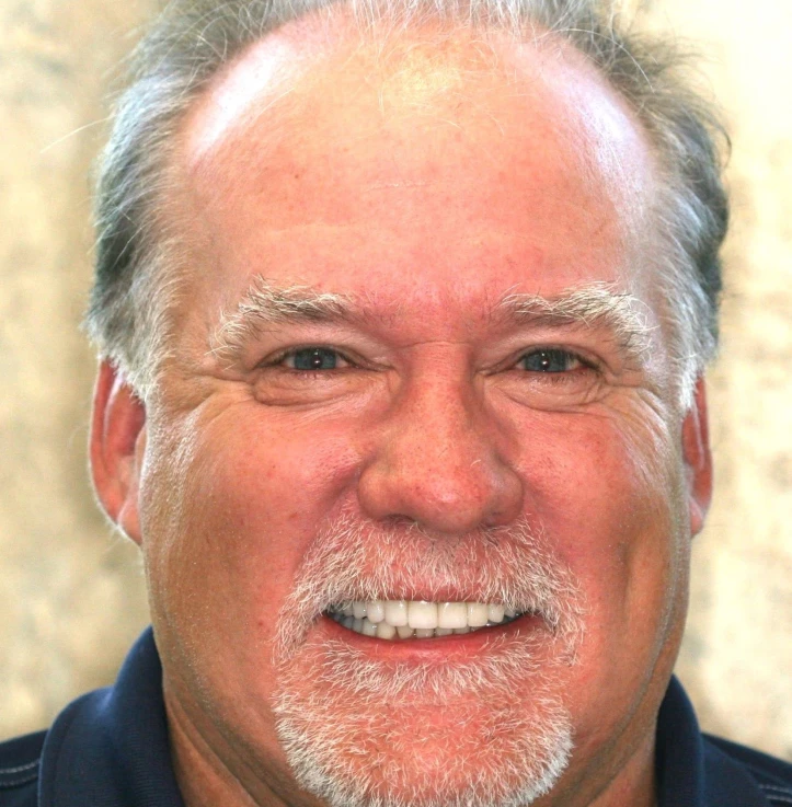 Close-up of a smiling middle-aged man with gray hair, a mustache, and beard.