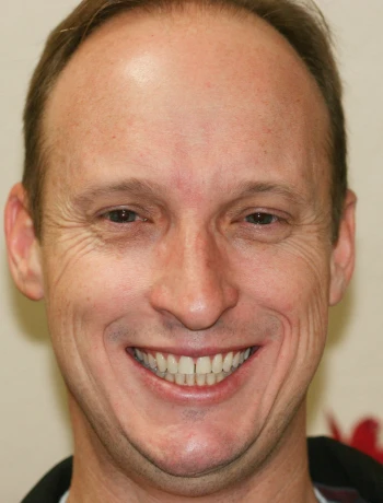 Smiling middle-aged man with short hair and light skin looking directly at the camera.