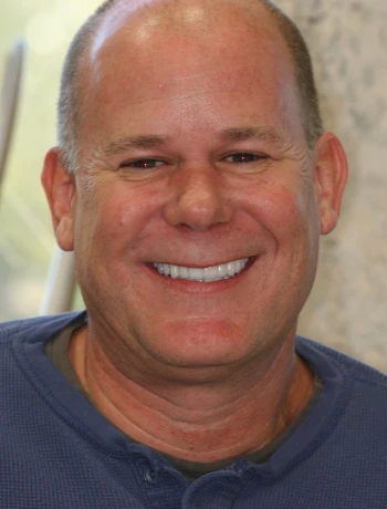 Smiling middle-aged bald man wearing a blue shirt.
