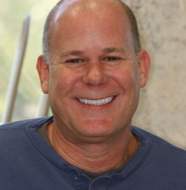 Smiling middle-aged man with short hair wearing a blue shirt.
