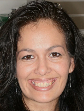 Close-up of a smiling woman with long dark hair, wearing black earrings.