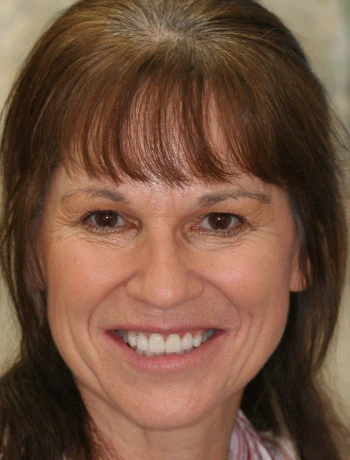 Portrait of a middle-aged woman with brown hair and bangs smiling at the camera.