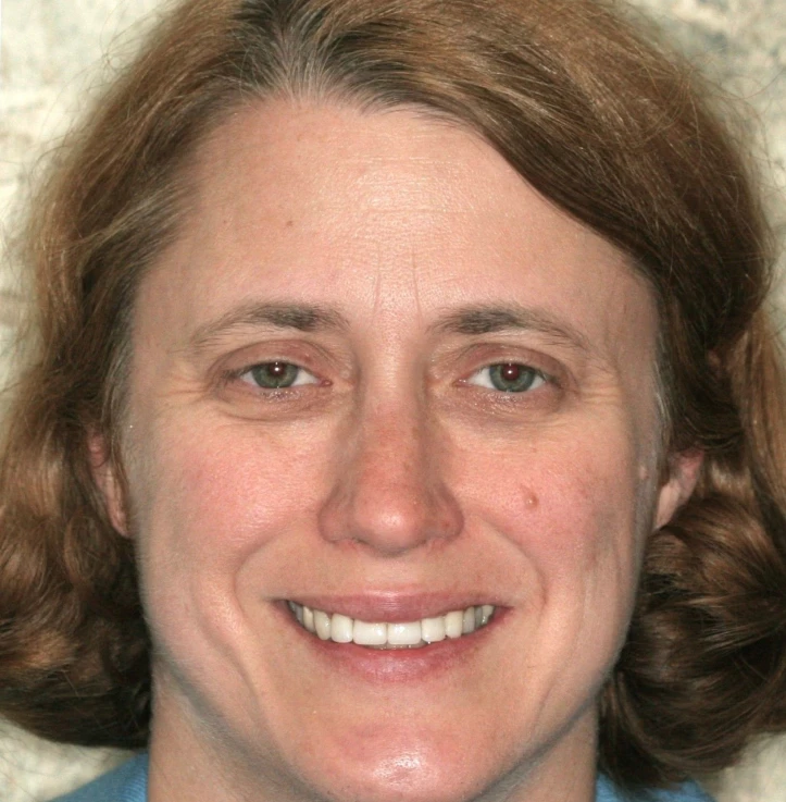Close-up of a smiling woman with short, light brown hair and light skin.