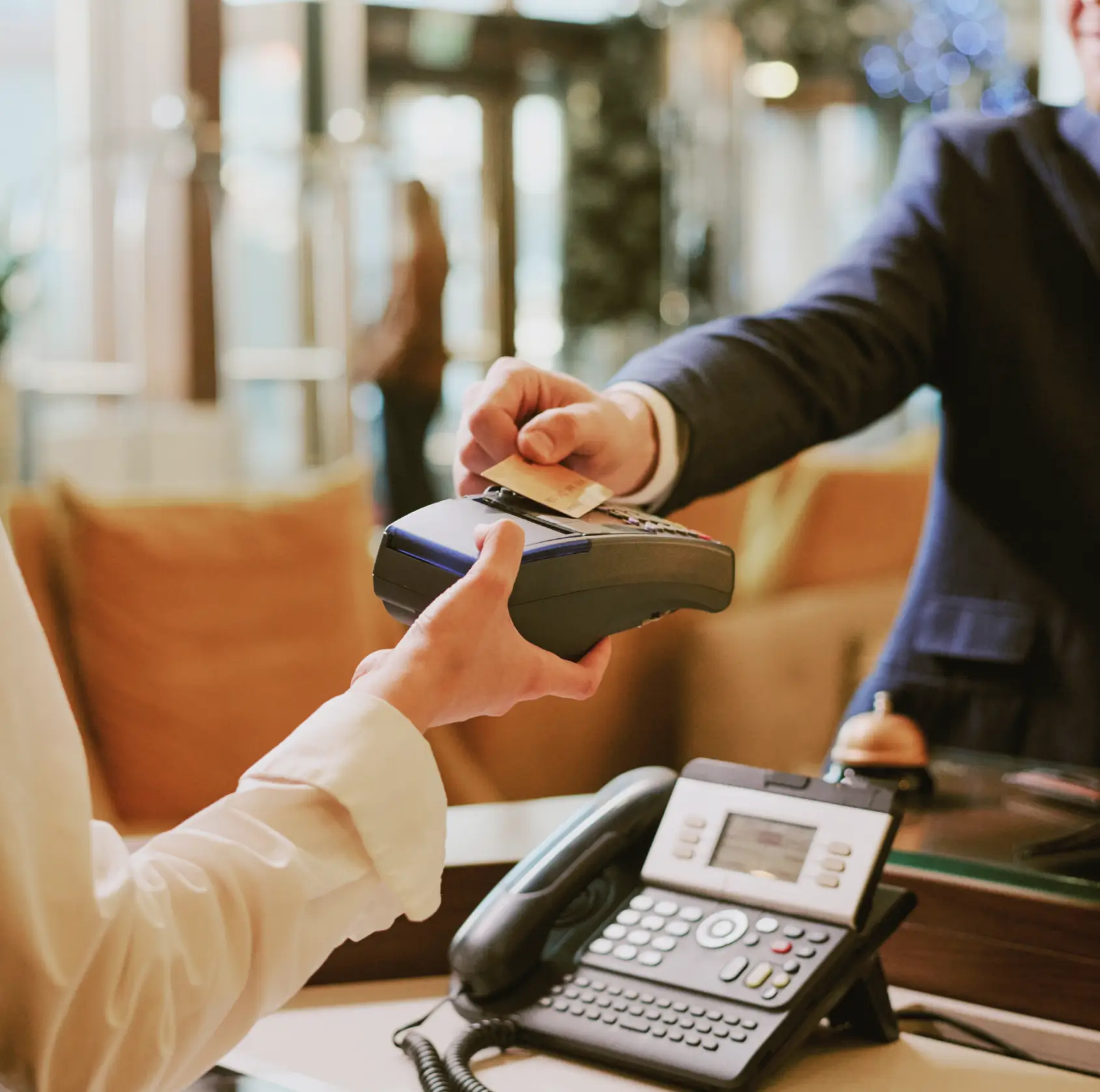 Person in business attire making a contactless payment with a card on a handheld card reader.