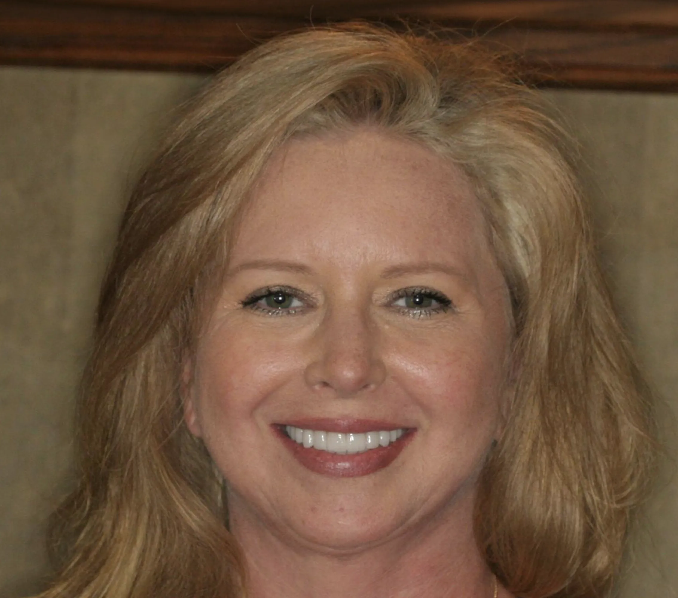 Close-up portrait of a smiling woman with long blonde hair and light makeup.