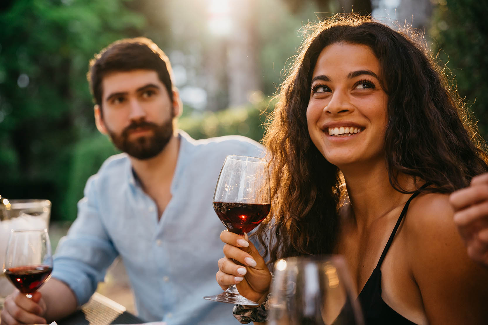 A young couple enjoys a glass of wine on a patio in summer.