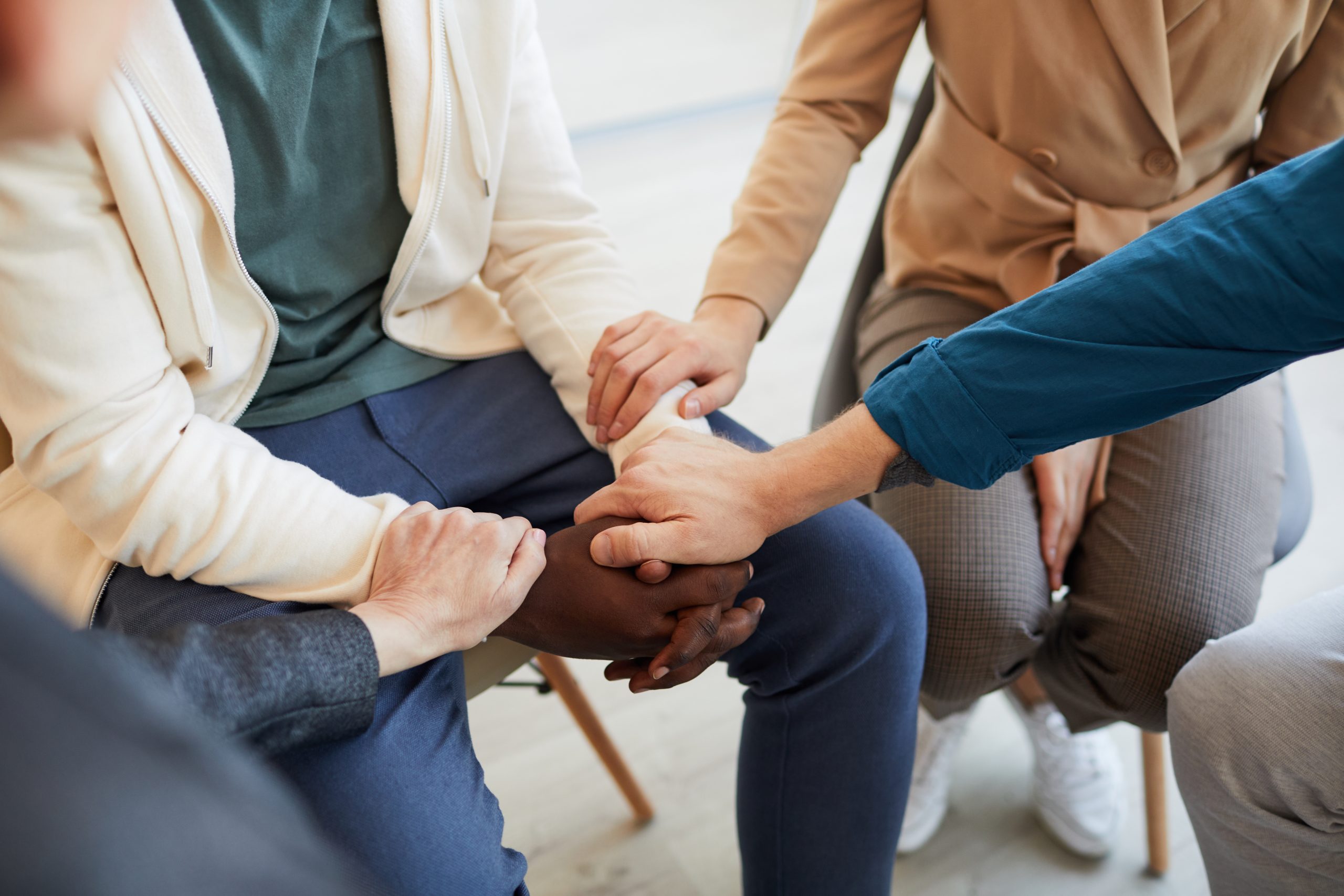 group of people putting their hands on a man's lap