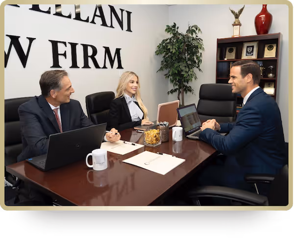 Three business professionals in a law firm office having a meeting around a table with laptops, notebooks, and coffee mugs.
