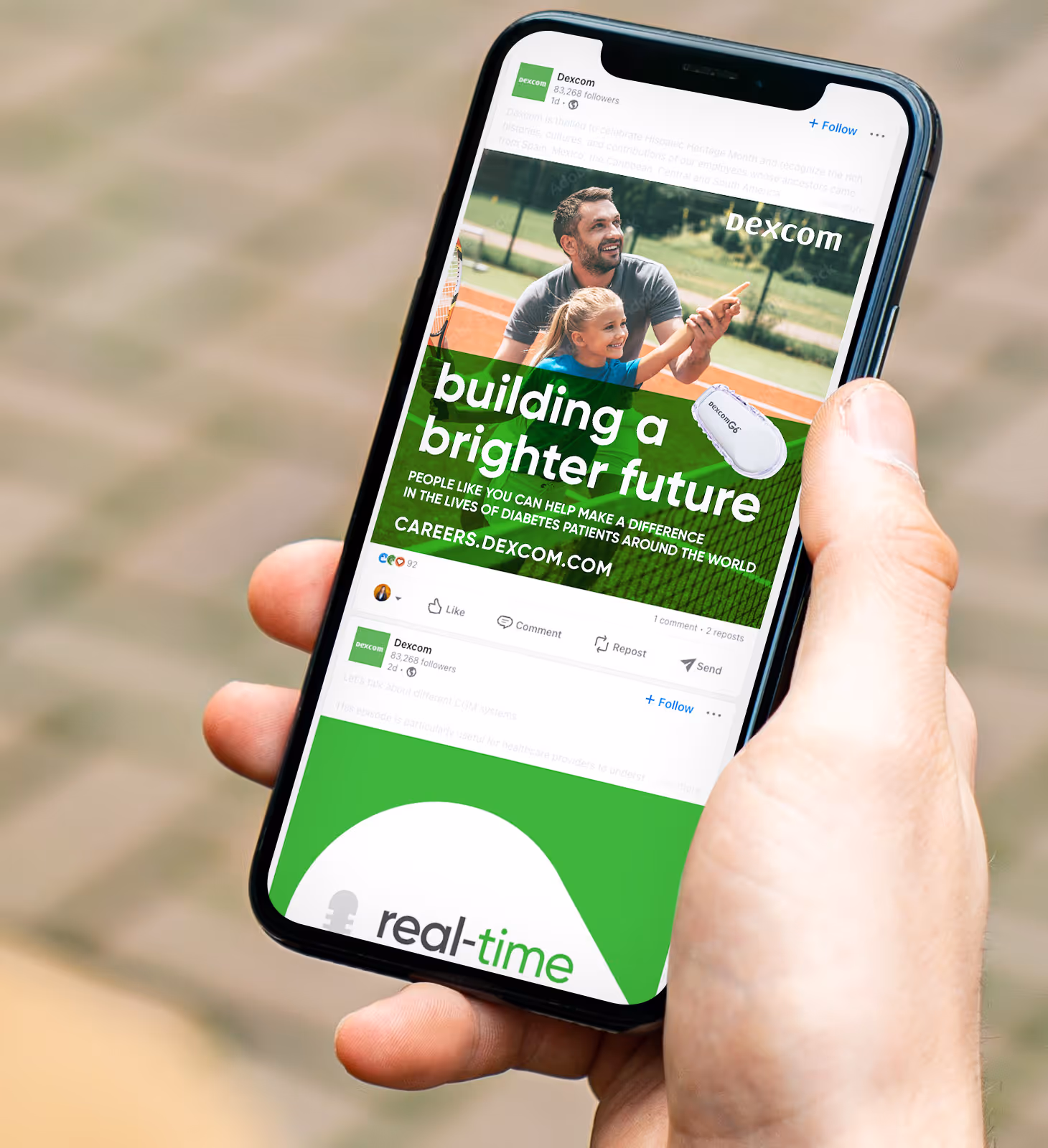 Hand holding smartphone displaying a Dexcom social media post with a man and child on a tennis court and text about building a brighter future for diabetes patients.
