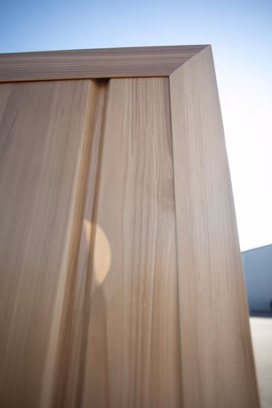 Close-up of the top corner of a wooden fence panel with clear blue sky in the background.
