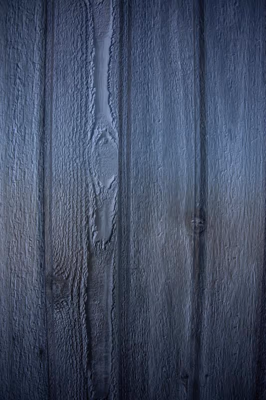 Close-up of dark blue painted wooden planks with visible grain and knots.