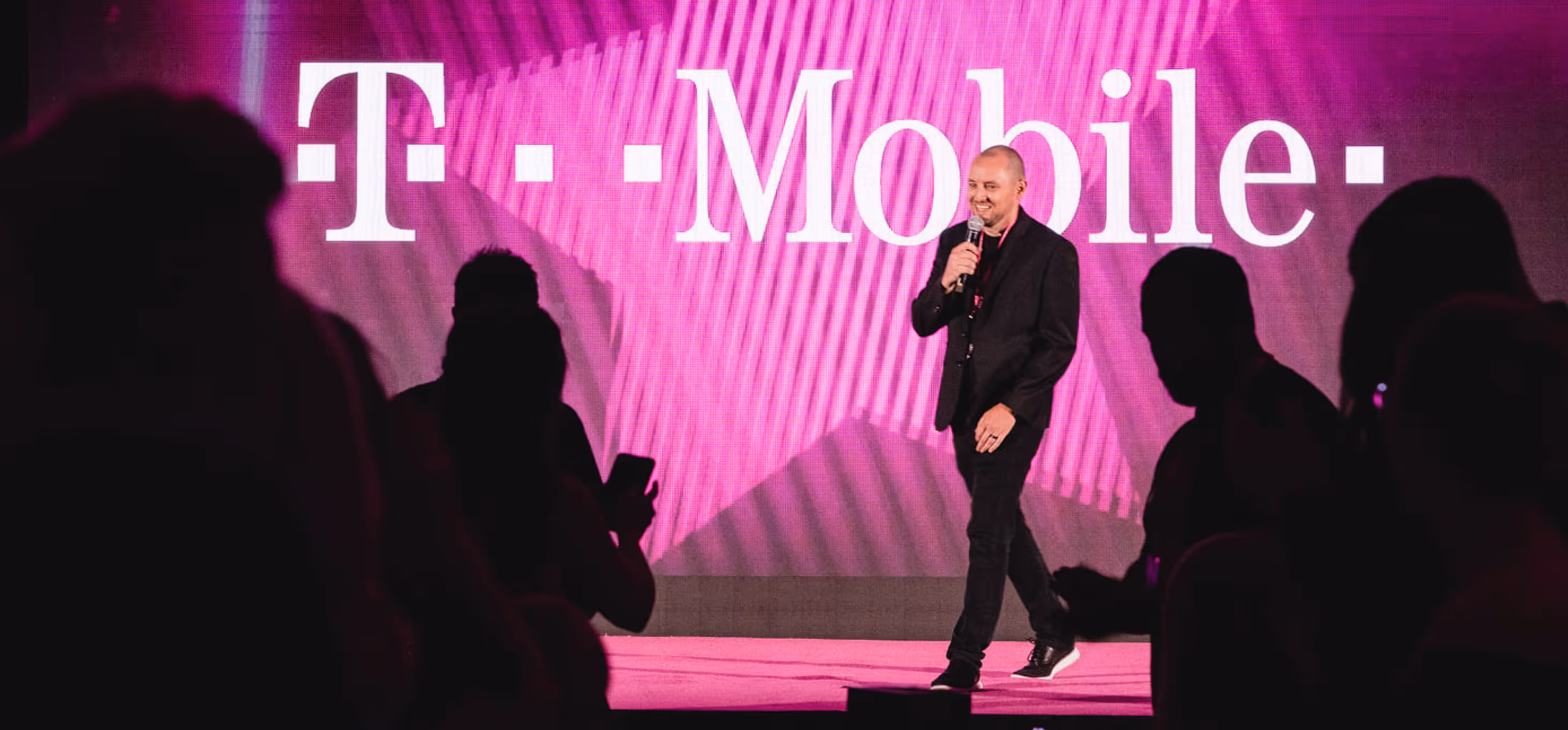 Drew walking onto stage with a microphone at a T-Mobile event