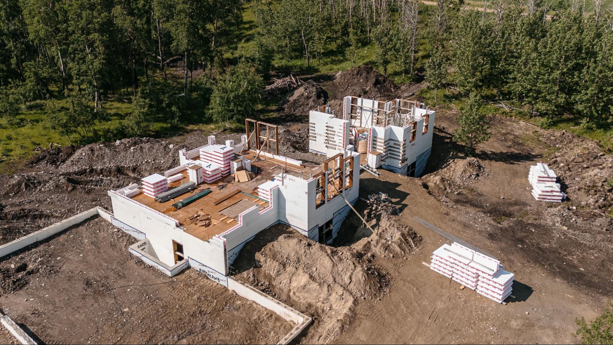A building still in construction, being built with SuperForm ICF, with a forest in the background.