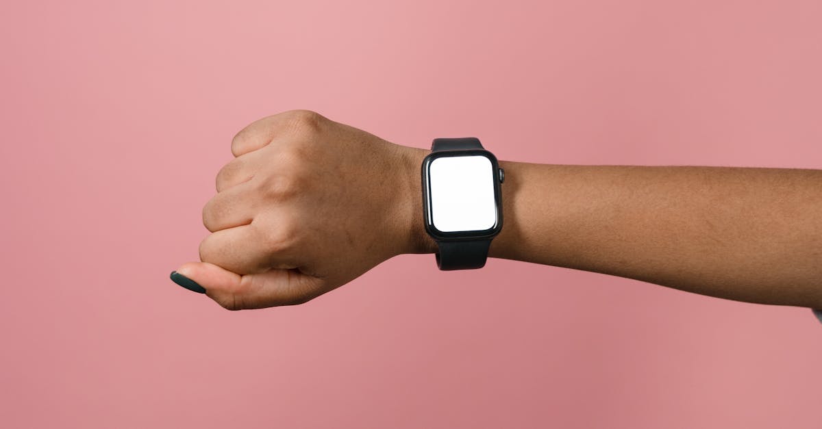 Hand displaying a smartwatch against a pink background, perfect for design mockups.