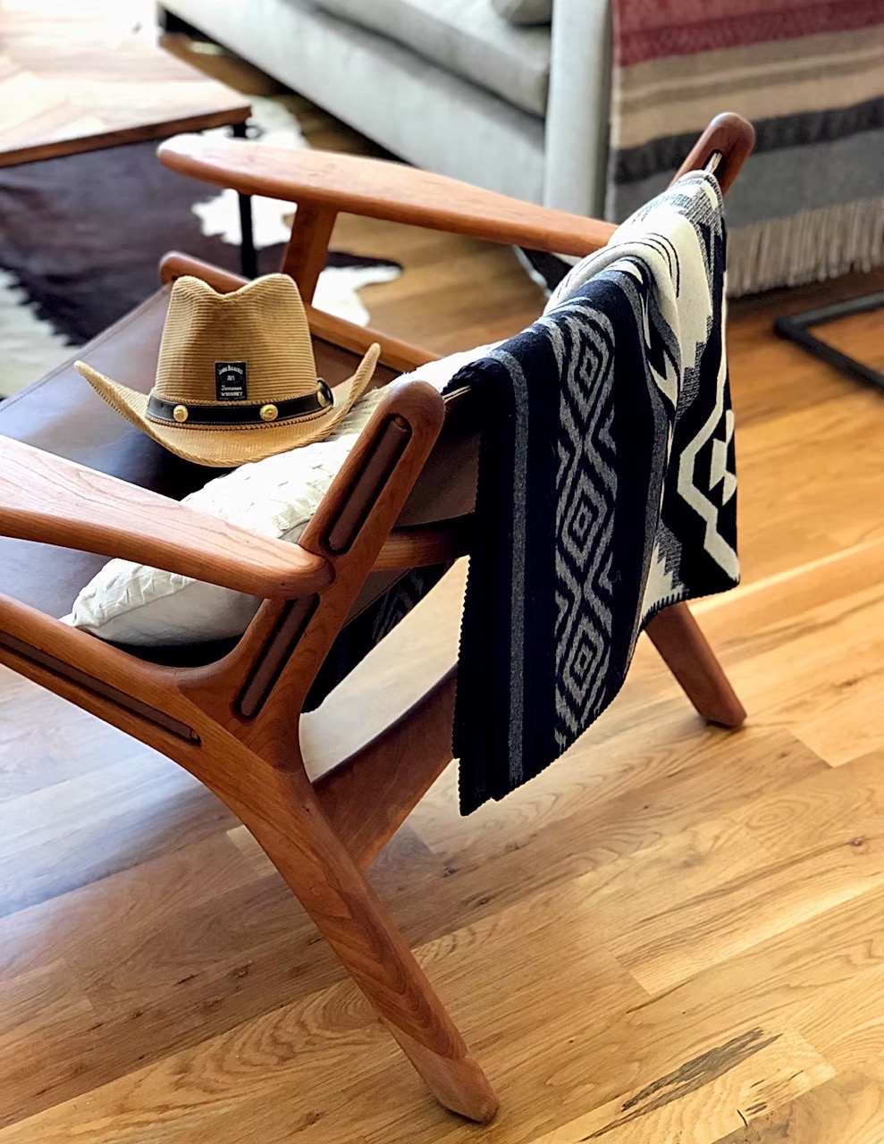 Western-style hat resting on a wooden chair in a cozy interior setting.