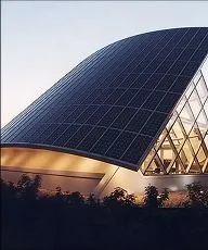 Modern building with a curved roof covered in solar panels and large glass windows.
