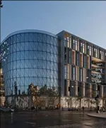 Modern building with a curved glass facade next to a rectangular structure with vertical design elements during dusk.