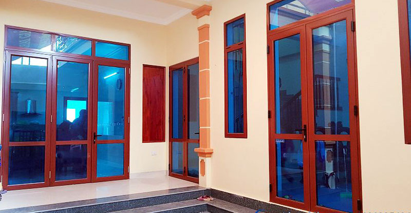 Thi công cửa nhôm vân gỗ lắp kính màu xanh đen
