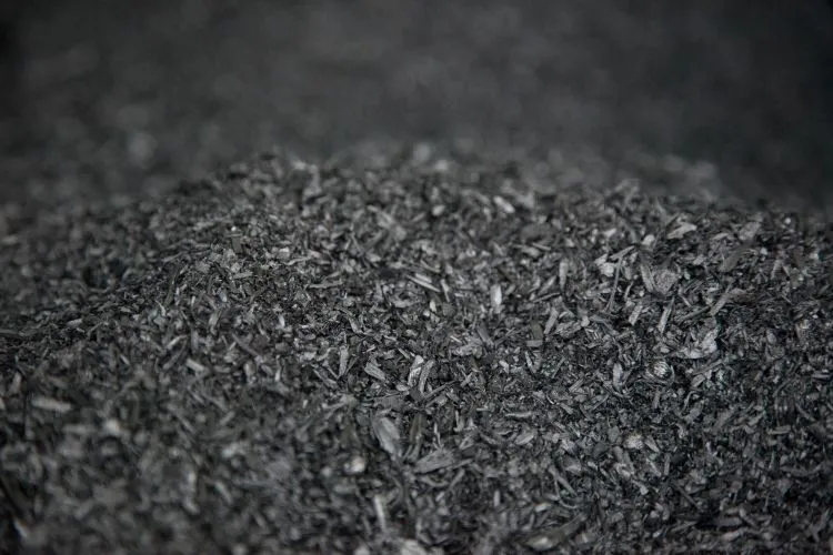 Close-up view of a pile of dark, fine, shredded organic material resembling biochar.