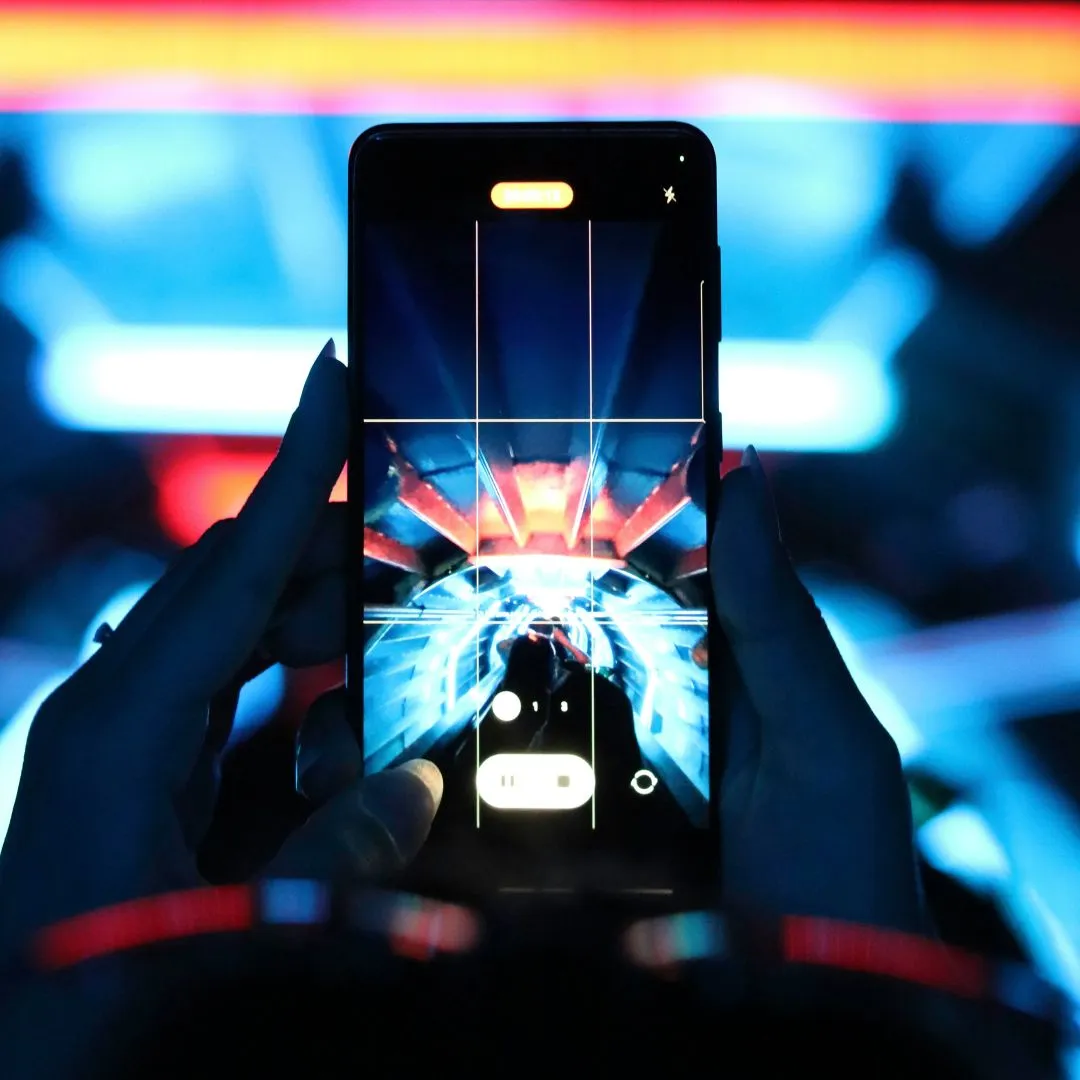 Hands holding a smartphone showing a tunnel with blue and red lights on its screen in a dark setting.