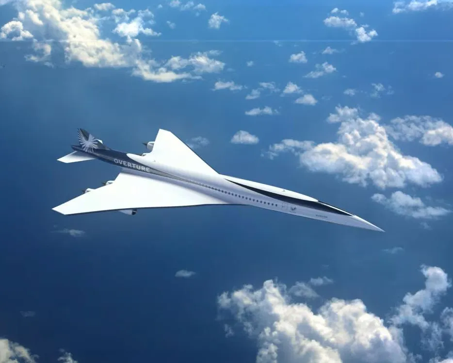 White supersonic airplane labeled OVERTURE flying above clouds in blue sky.