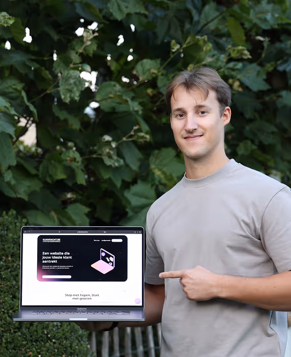 Founder Housen Maxim die buiten in de tuin staat met zijn laptop waar deze site van klikkracht.be te zien is terwijl hij ernaar wijst