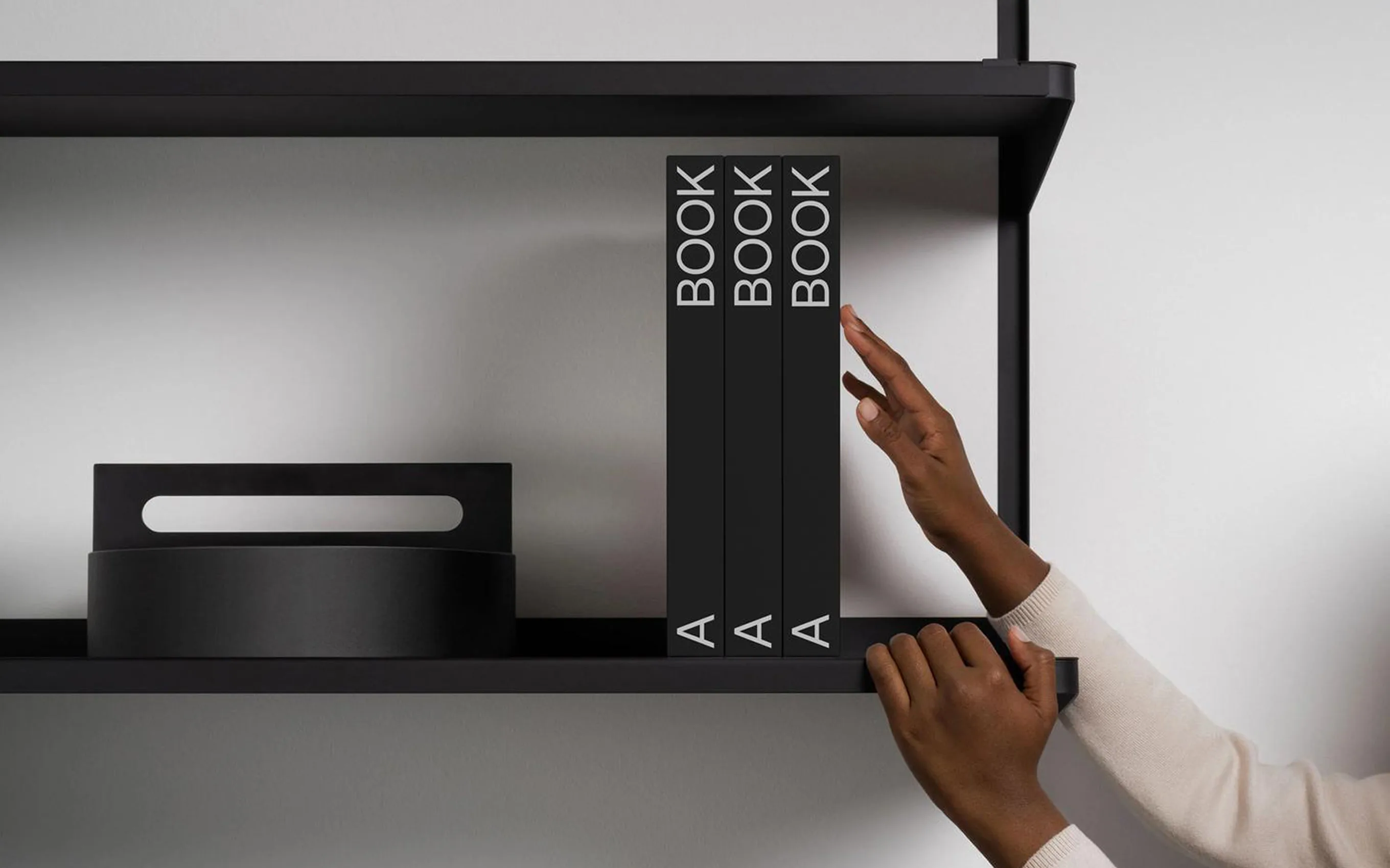 A person stretching their arm to grab a book from a high shelf in a library.