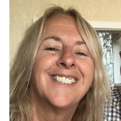 Smiling woman with blonde hair in a light-colored room.