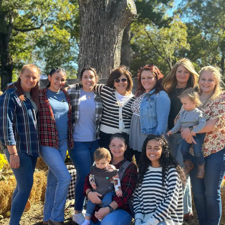 Group of women friends smiling together in a sunny outdoor setting.